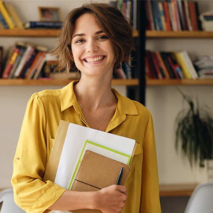 mujer sonriente con cuadernos en el brazo