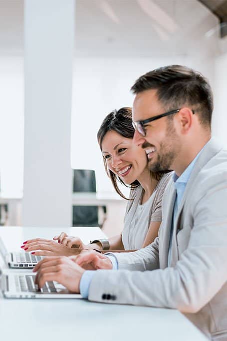 hombre y mujer sonrientes frente a una computadora