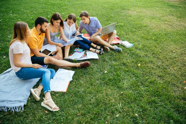 Grupo de estudiantes adolescentes en atuendos casuales estudiando en el césped