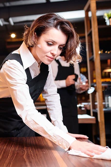 joven limpiando mesa de restaurant