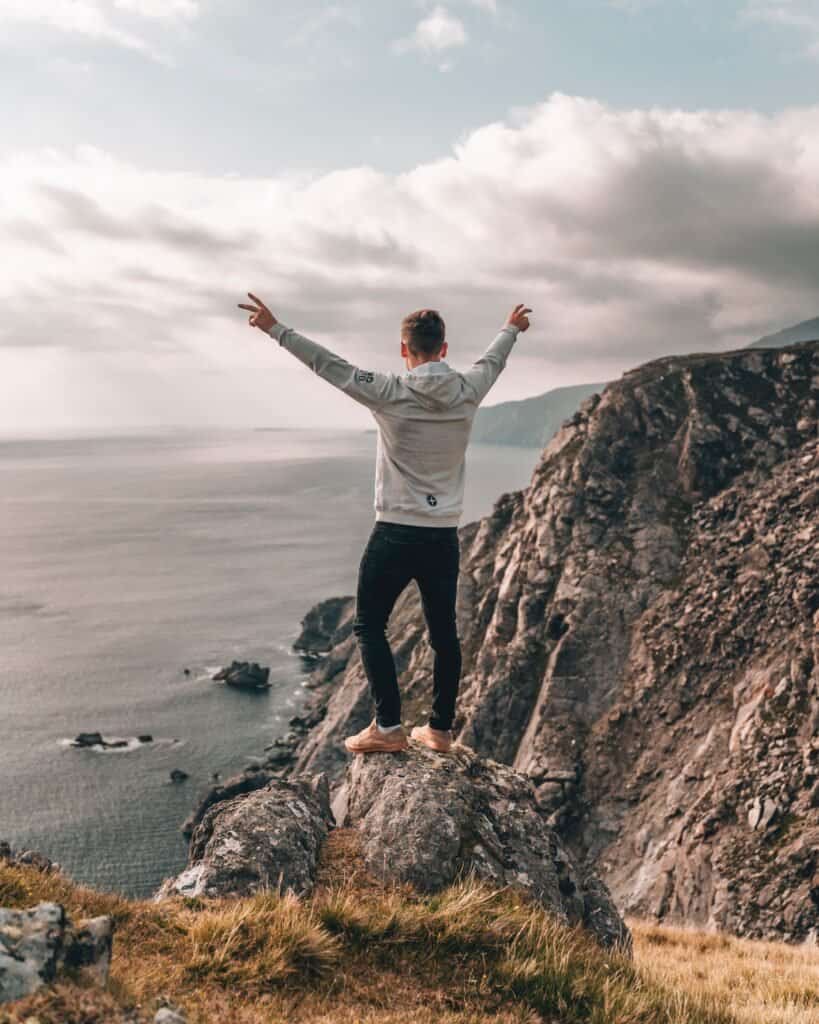 joven feliz mirando al mar desde un acantilado