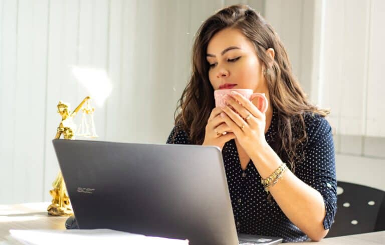 mujer frente a computadora tomando cafe