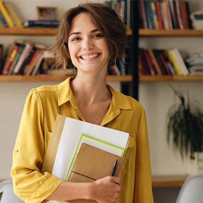 mujer sonriente con cuadernos en el brazo