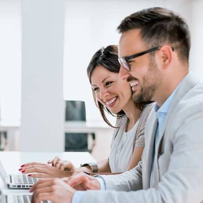 hombre y mujer sonrientes frente a una computadora