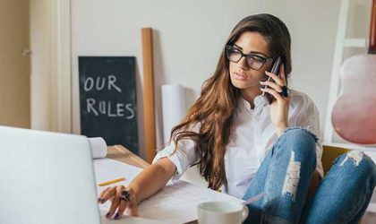 mujer hablando por telefono frente a una computadora