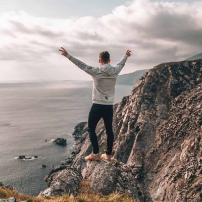 joven feliz mirando al mar desde un acantilado