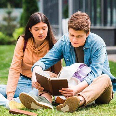 pareja de estudiantes leyendo al aire libre