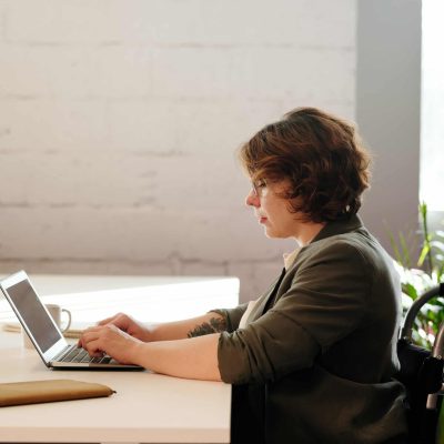 mujer en silla de ruedas escribiendo en laptop